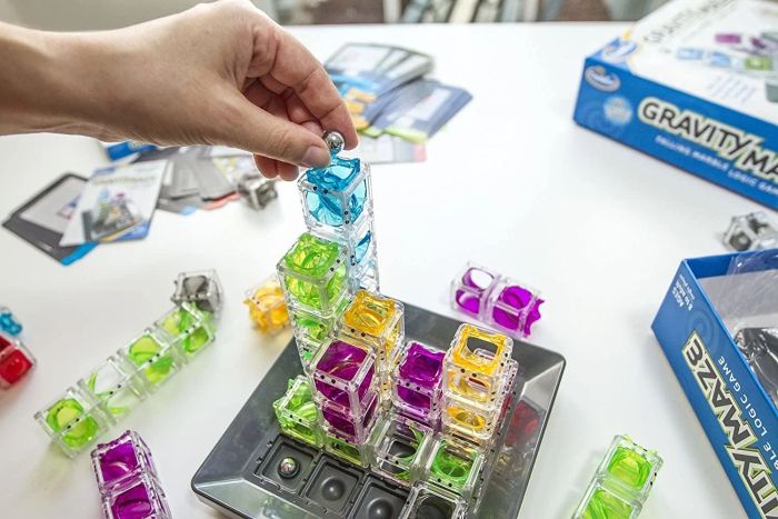 An image of a person placing a marble atop a stack of clear cubes on the game's board.
