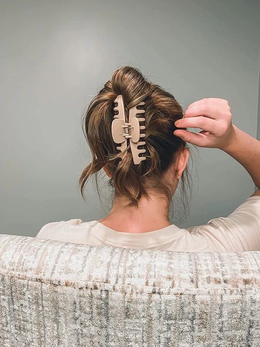 A reviewer styling their light brown hair with a light pink claw clip.