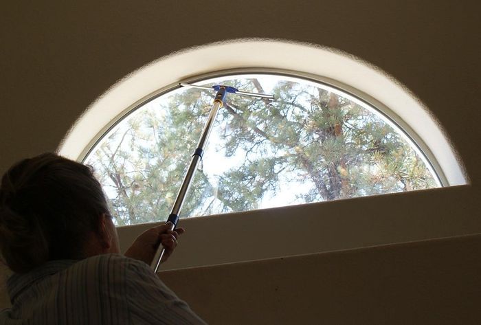 A reviewer uses the extendable squeegee to clean a window.