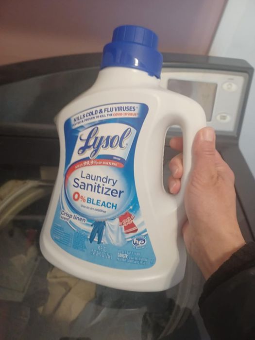 A reviewer holding a bottle of laundry sanitizer