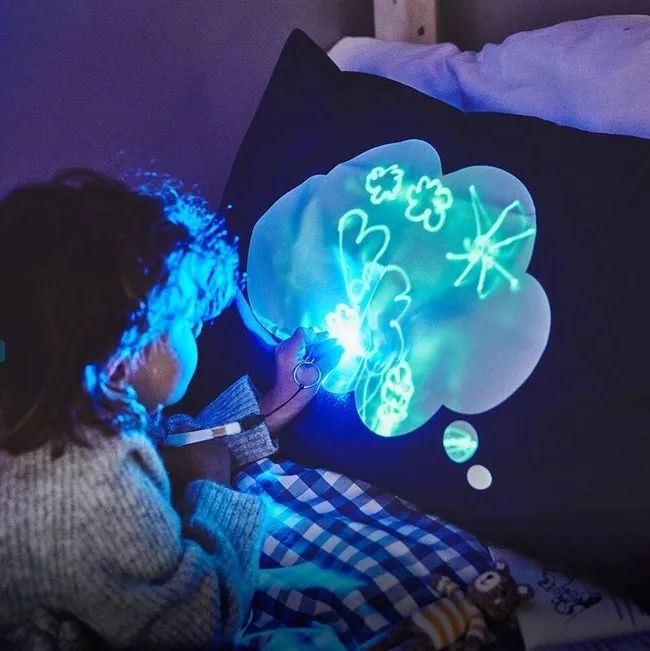 A child drawing on a glowing pillowcase in the dark