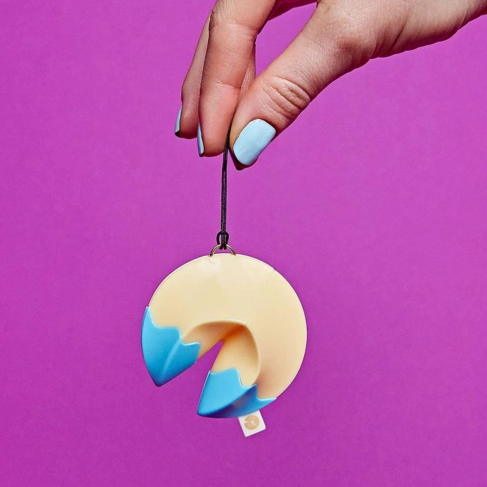 A fortune cookie toy hanging from a hand