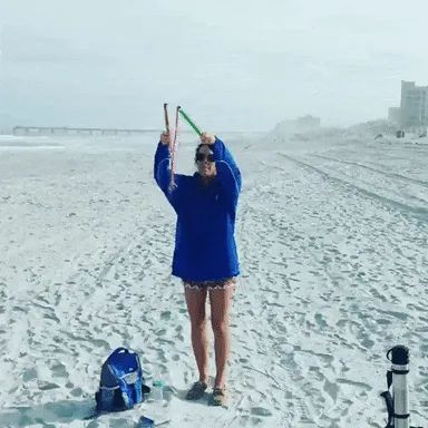 A reviewer using the bubble wand to create enormous bubbles on the beach