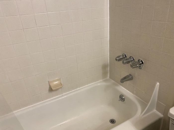 The same reviewer's bathroom after cleaning, with the tiles and bathtub spotless, showing no signs of staining or dirt.