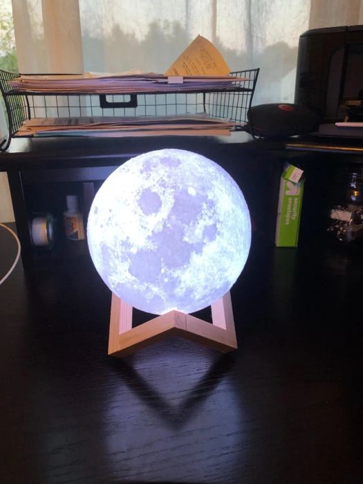 Moon-shaped light resting on a wooden base