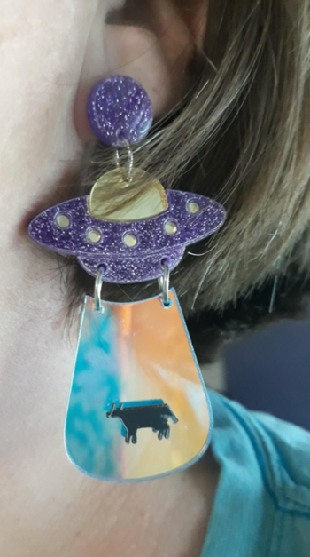 A reviewer's earring shaped like a spaceship beaming up a cow