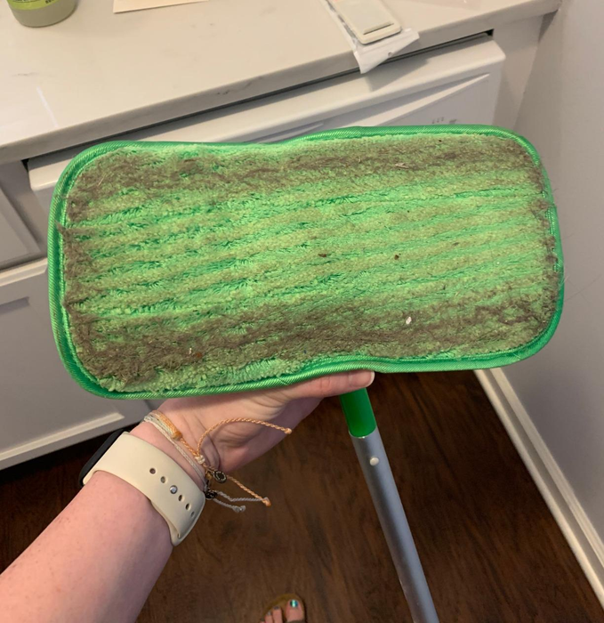 A reviewer’s Swiffer mop, with the attached pad, showing all the dirt it has collected