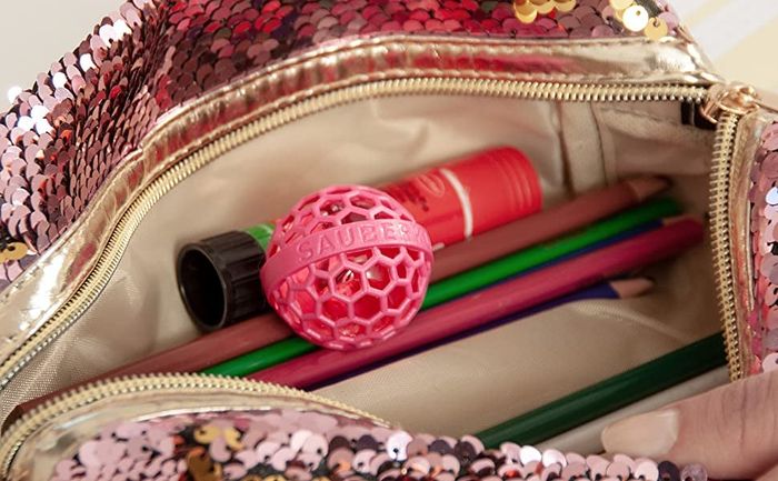 A pink sequin bag opened to reveal the pink Clean Ball inside.
