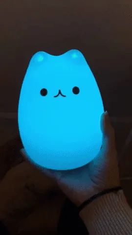 A gif of a reviewer holding the cat-shaped light as it changes colors