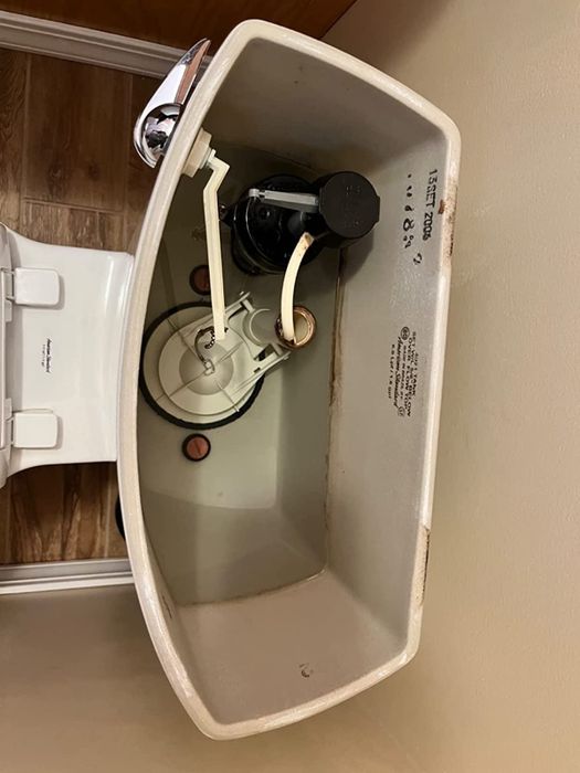 An image showing the same toilet tank after cleaning, now free from stains and filled with clear water.