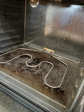 A greasy oven interior covered in visible stains and grime, including on the heating element