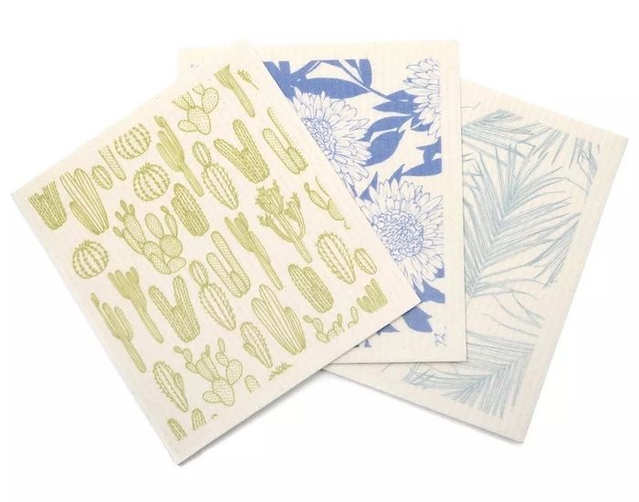Three decorative dishcloths featuring distinct patterns: cacti, floral, and palm leaves
