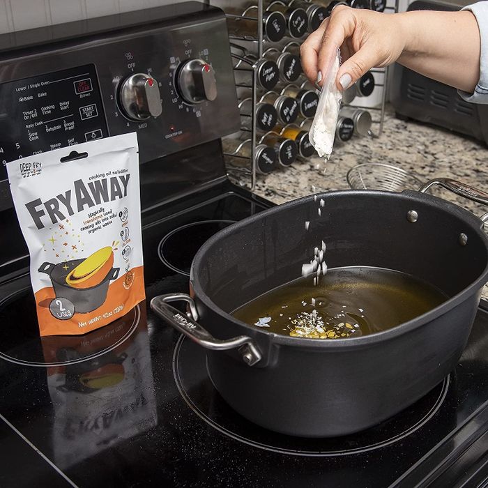 A model’s hand sprinkling white flakes into a pot of hot oil.