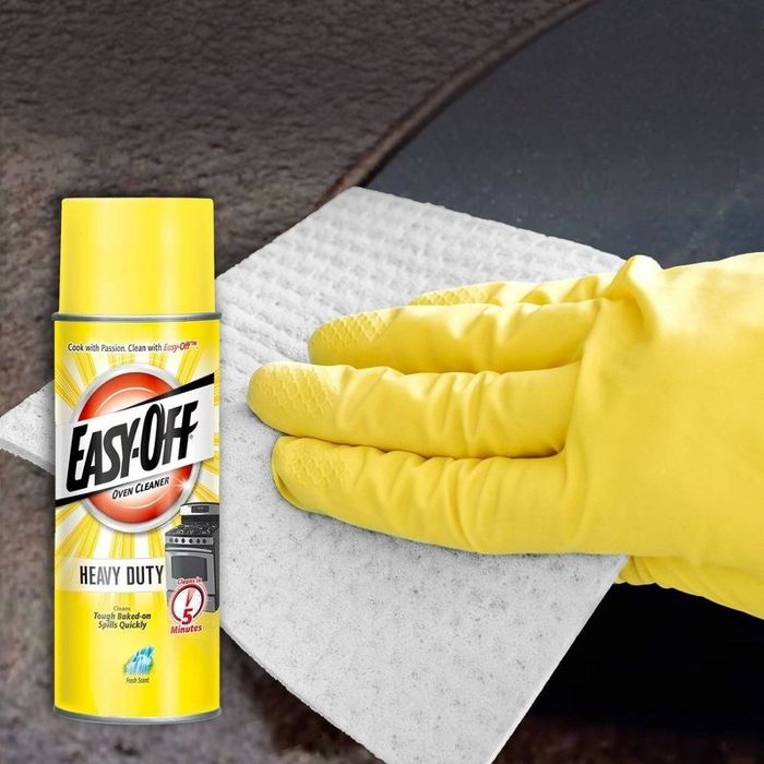 a person cleans the oven's surface using the cleaner