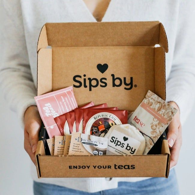 A model showcasing an open box filled with an assortment of tea bags.