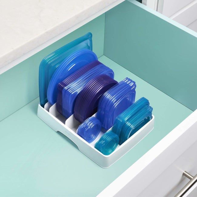 The organizer neatly storing six different sizes of container lids inside a drawer.
