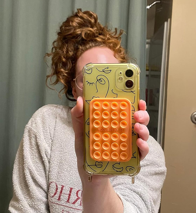 A person holding a phone with a suction cup mount attached.