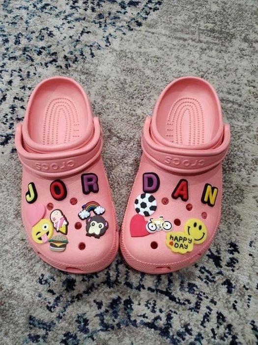 A reviewer's pink Crocs, decked out with colorful Jibbitz charms.