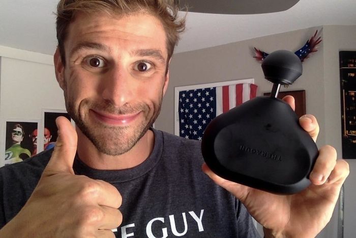 A reviewer holding the Theragun Mini massager, showing its ease of use and portability.
