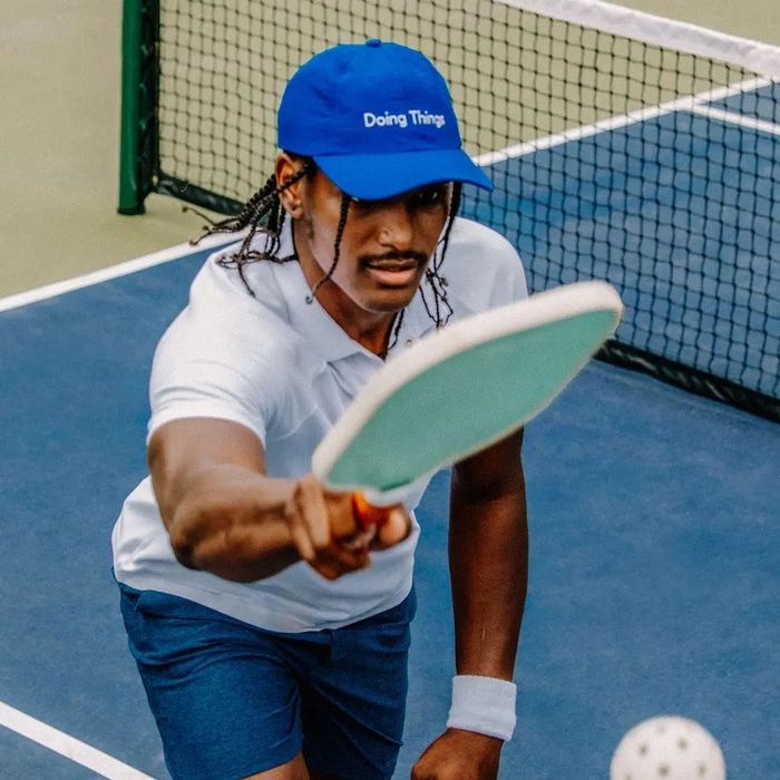 A model hitting a ball with a paddle while sporting the cap.