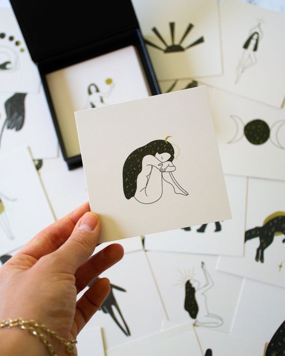 A model holding one of the meditation cards, showcasing an illustration of a peaceful woman.