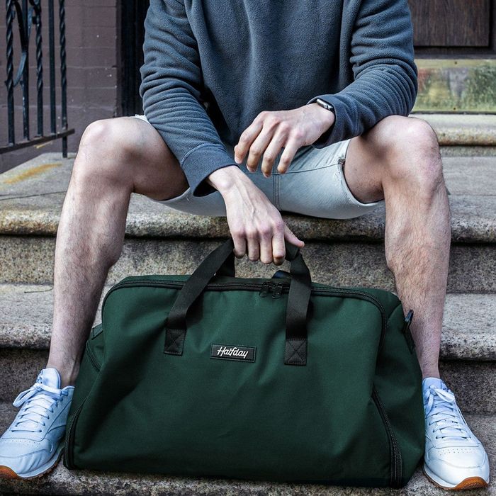 A model sitting with the green duffel bag.