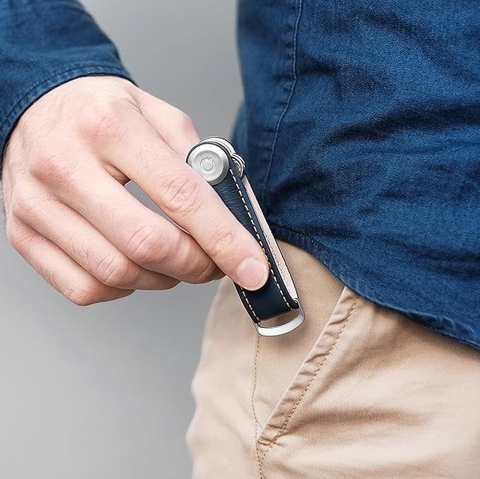 A person inserting a compact, foldable pocket knife with a sleek handle into their pocket. Ideal for everyday carry and practical tasks.