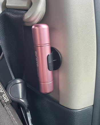 A pink cylindrical device mounted on a car's interior