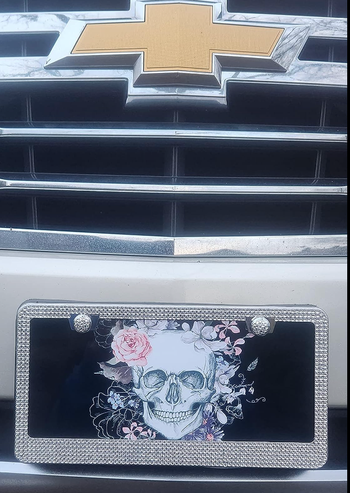 The silver version of the bedazzled license plate frame mounted on a car.