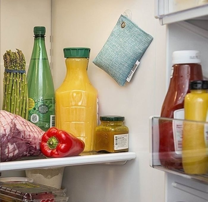 A blue fabric deodorizer pouch hanging inside a refrigerator.