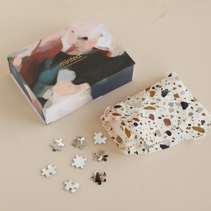 A printed box and pouch with several puzzle pieces spilling out.