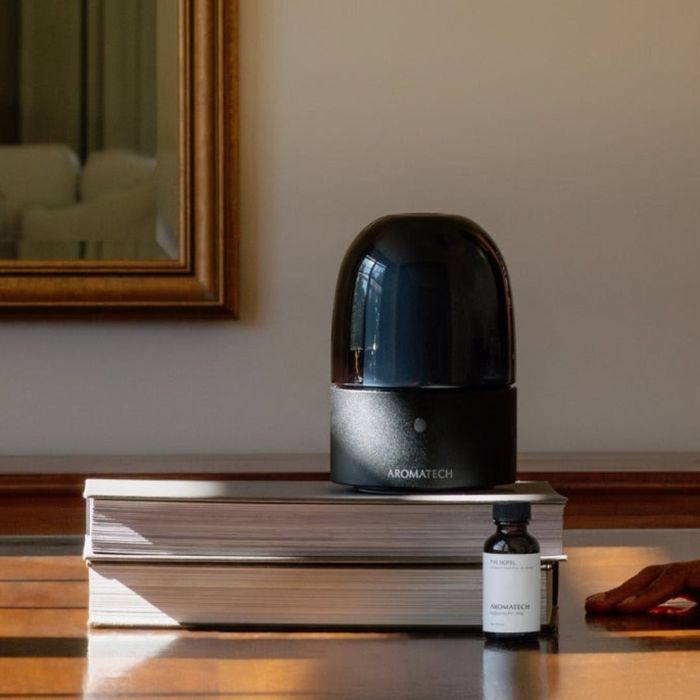 An aromatherapy diffuser and essential oil bottle placed on a table next to a stack of books. Perfect for filling any space with a delightful fragrance.