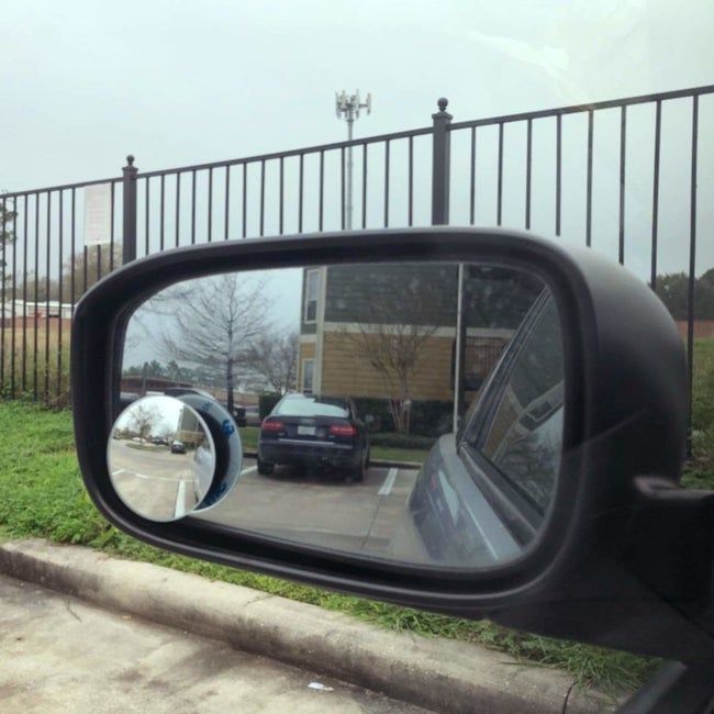 A small circular mirror attached to the side mirror of a car