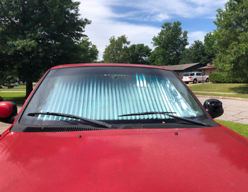A reviewer’s image showing the car from the outside, highlighting the reflective surface of the sunshade.