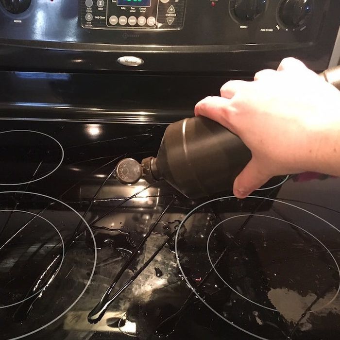 A blogger’s hand pouring hydrogen peroxide over a glass cooktop.
