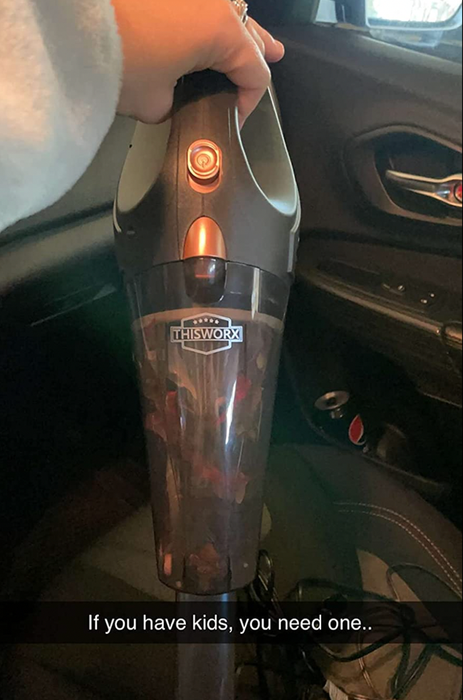 A reviewer holding a small black-handled vacuum
