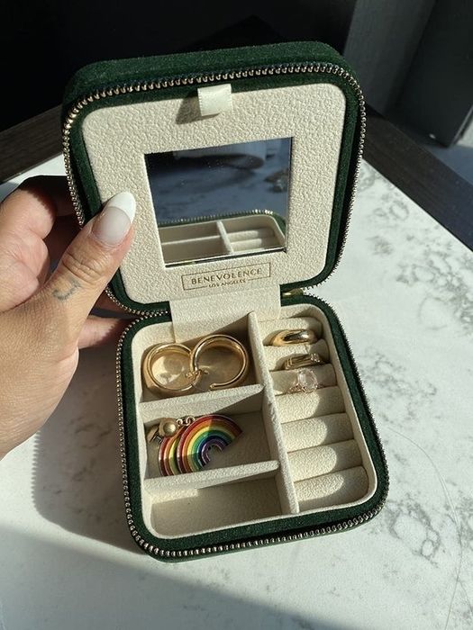 A reviewer's green velvet jewelry case holding two pairs of earrings and three rings.