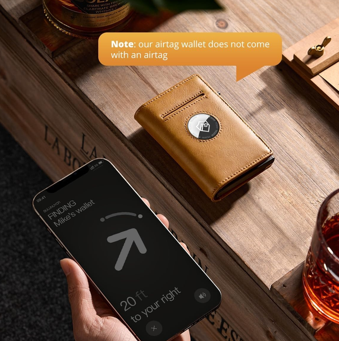 A person shows a phone with the AirTag tracking app open. A wallet featuring a dedicated AirTag slot sits on the table. Note: AirTag not included with wallet.