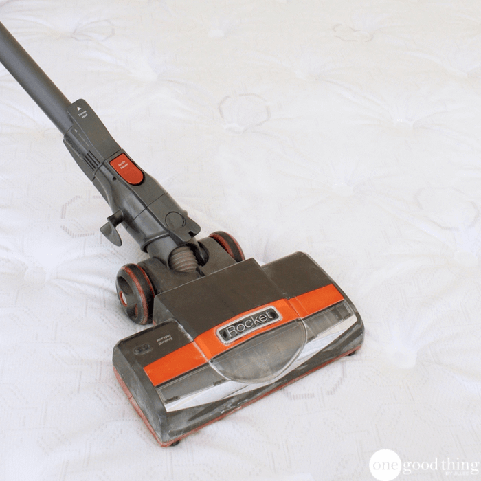 A vacuum being used on a mattress.