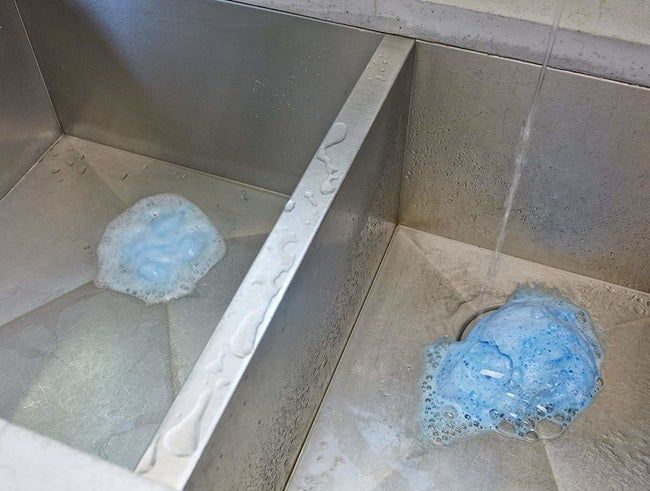 A drain filled with frothy blue bubbles inside