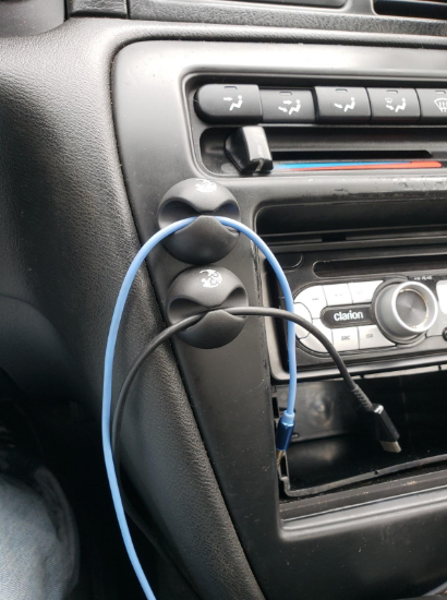 A photo from a reviewer showing the clips attached to a car dashboard, holding two charger cables neatly in place.