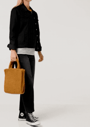 A model carrying a tan sherpa bag.