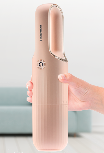 A model’s hand holding the pink vacuum with its cover on.