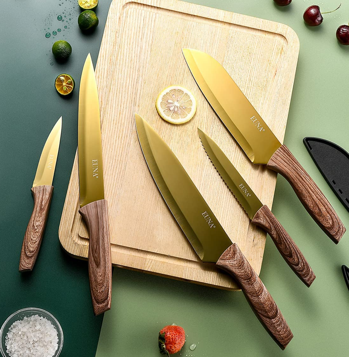 A gold knife set displayed on a cutting board, surrounded by various ingredients.