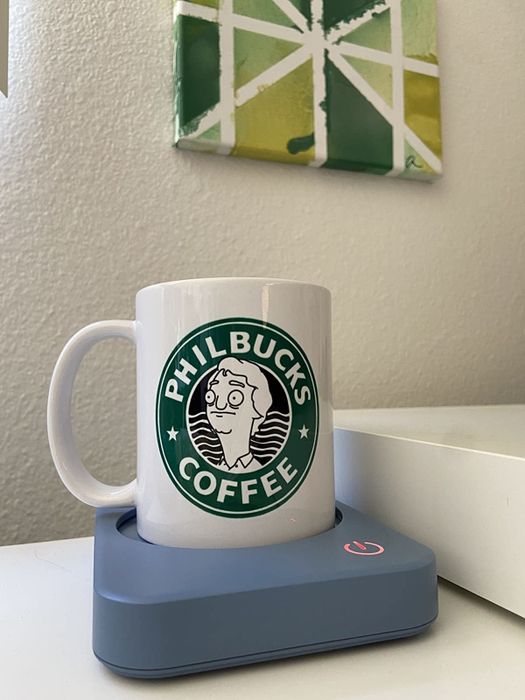 A mug filled with coffee sitting on a blue warmer.