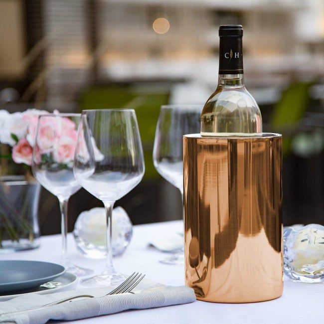 A beautifully set table with a copper wine bucket placed carefully, holding a chilled bottle of wine.