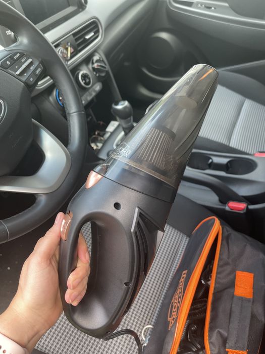 The writer demonstrates holding the portable vacuum.