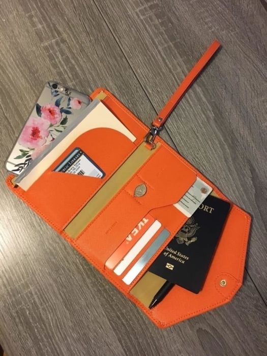 A reviewer photo showing the travel wallet open, displaying multiple compartments for passport, cards, money, phone, and more.