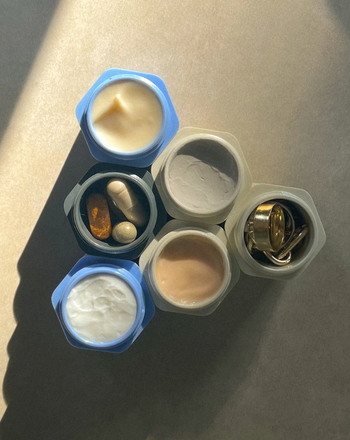 blue and white mini capsules containing skincare creams, vitamins, and jewelry
