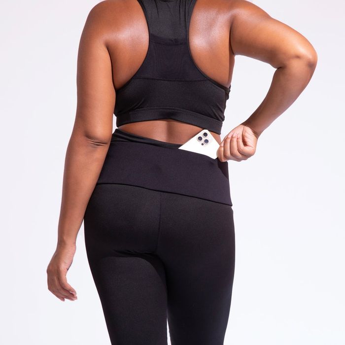 A model demonstrates the PocketCor belt in black, taking a phone out of the back pocket.